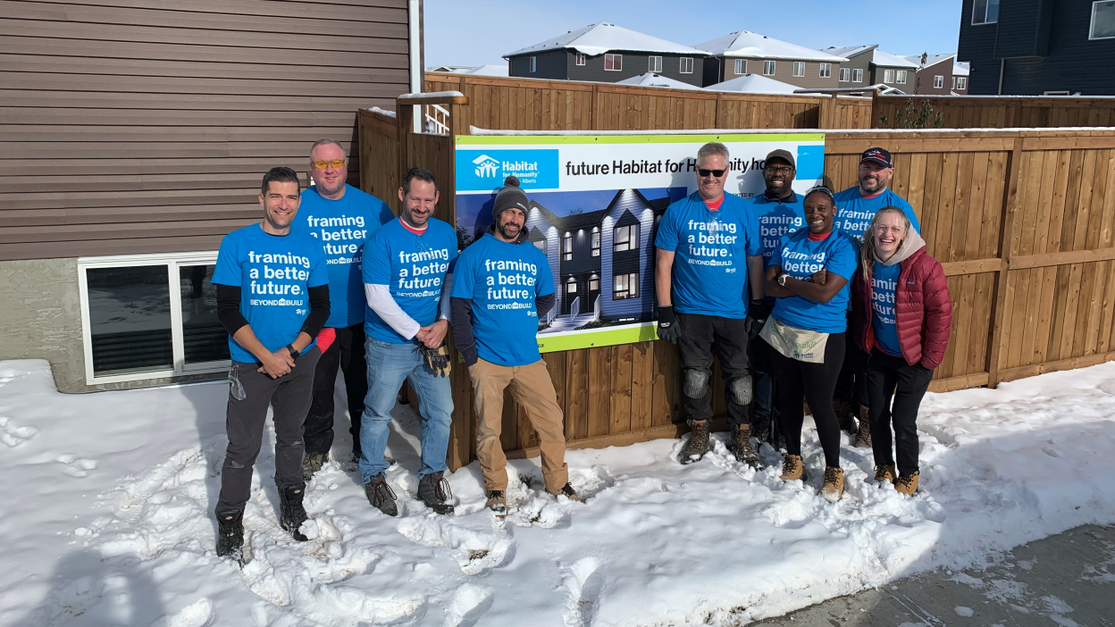 A group of Honda employees doing charitable work pose outside in the snow. 